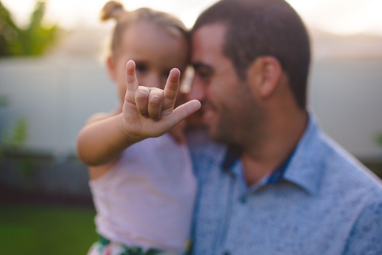 A dad with his young daughter doing the rock and roll sign.