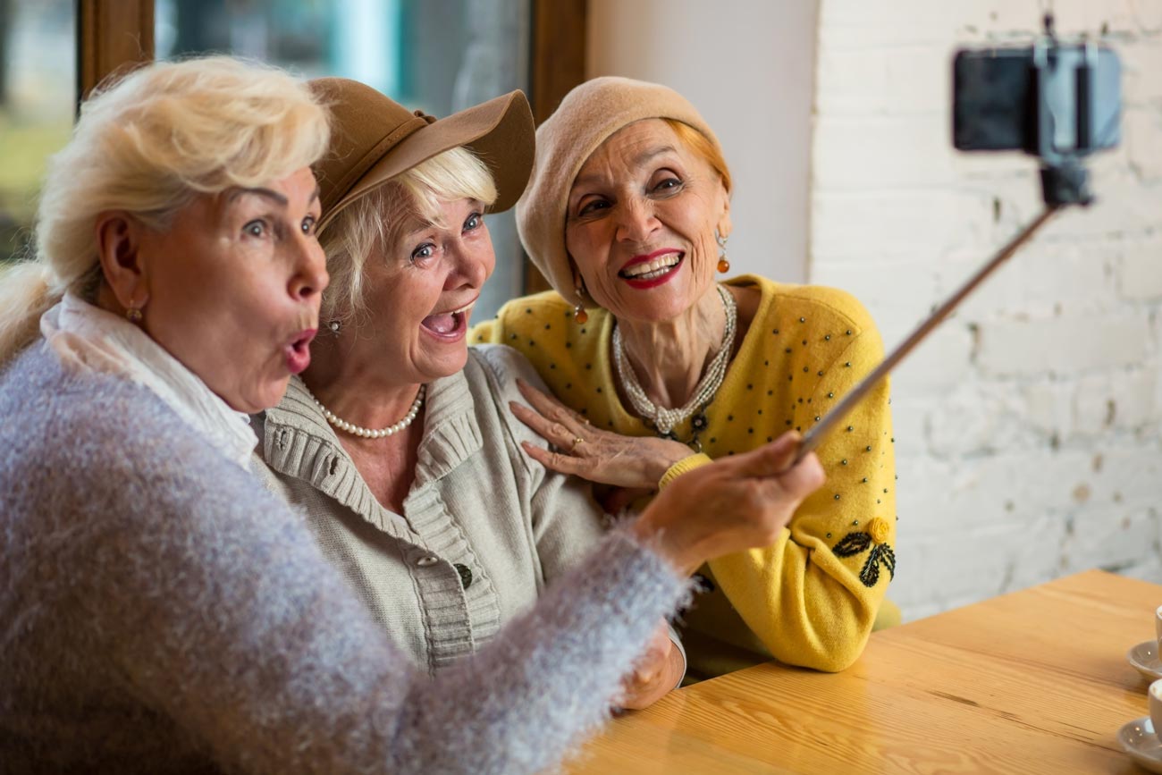 Three ladies having fun with a selfie stick.