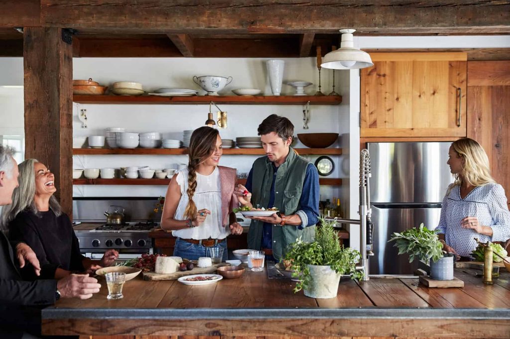 Financial Family And Friends Cooking Together In Rustic Farmhouse Kitchen